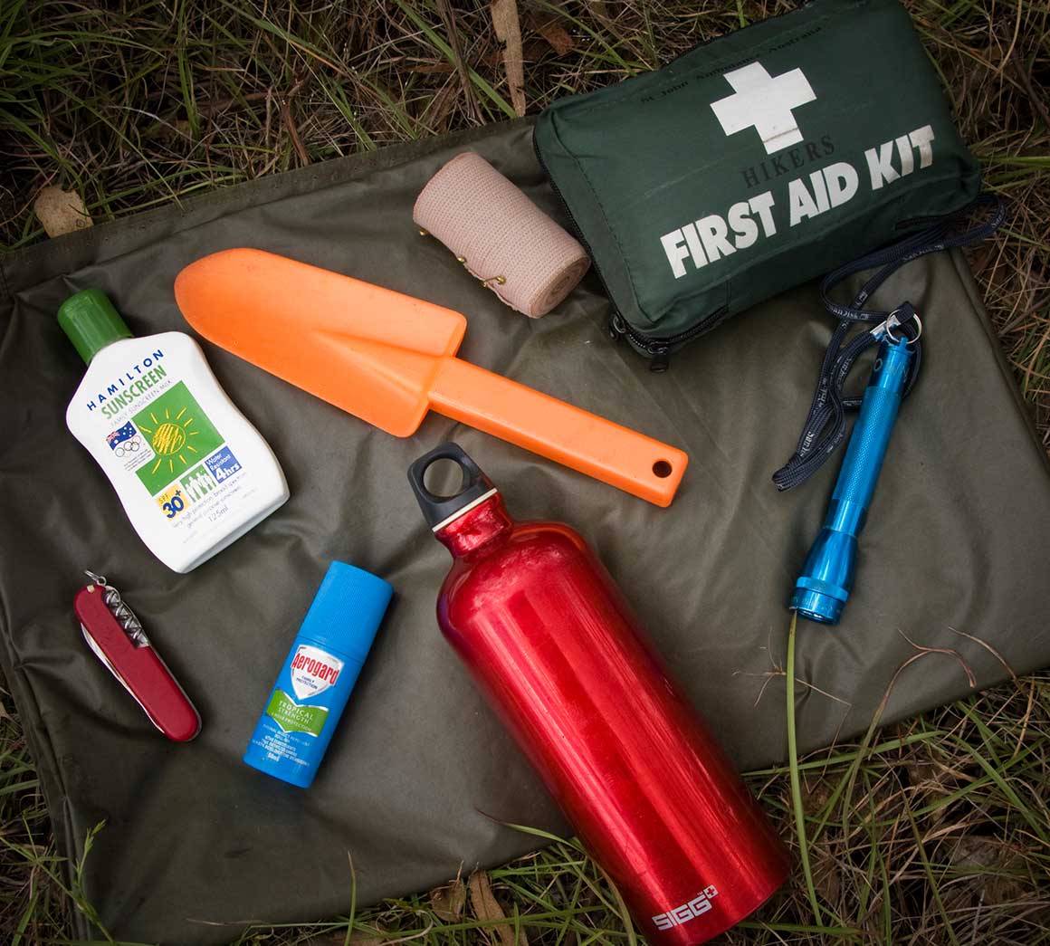 First aid kit, pocket knife, insect repellent, water bottle, sunscreen, bandage, torch and shovel